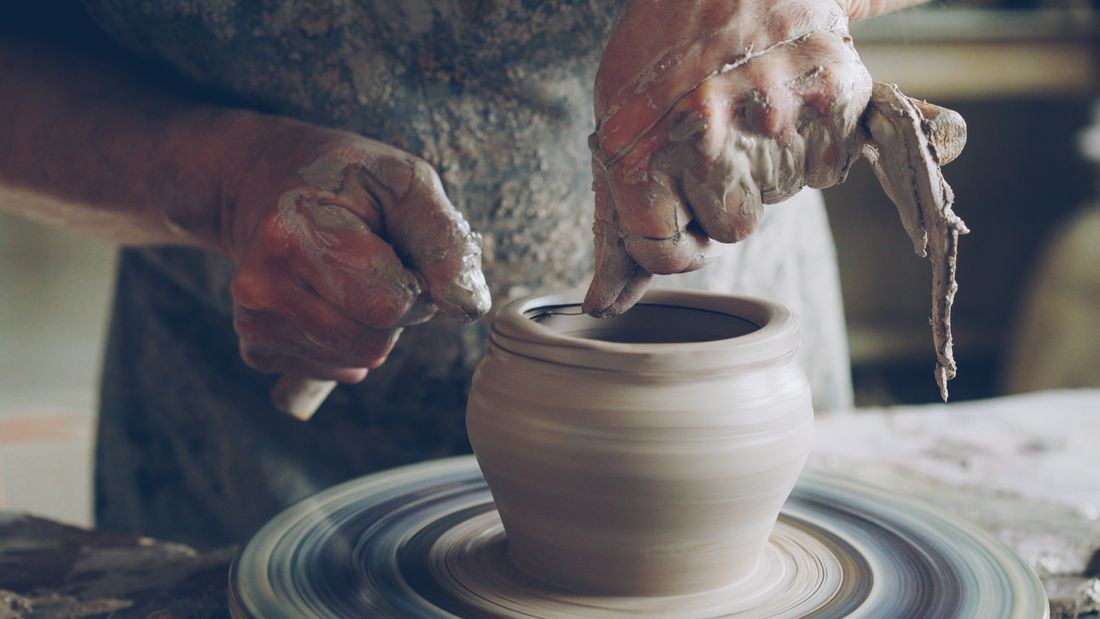 Close-up of a potter's hands shaping wet clay on a spinning wheel