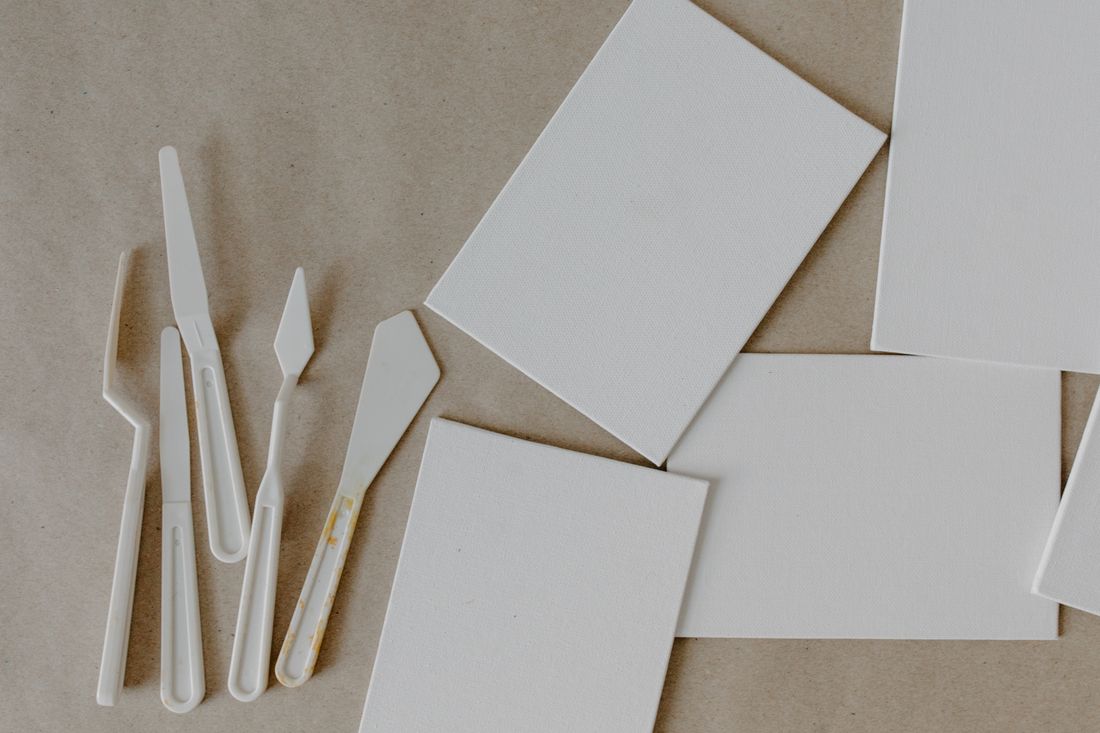 Blank stretched canvases and palette knives arranged on a plain studio table