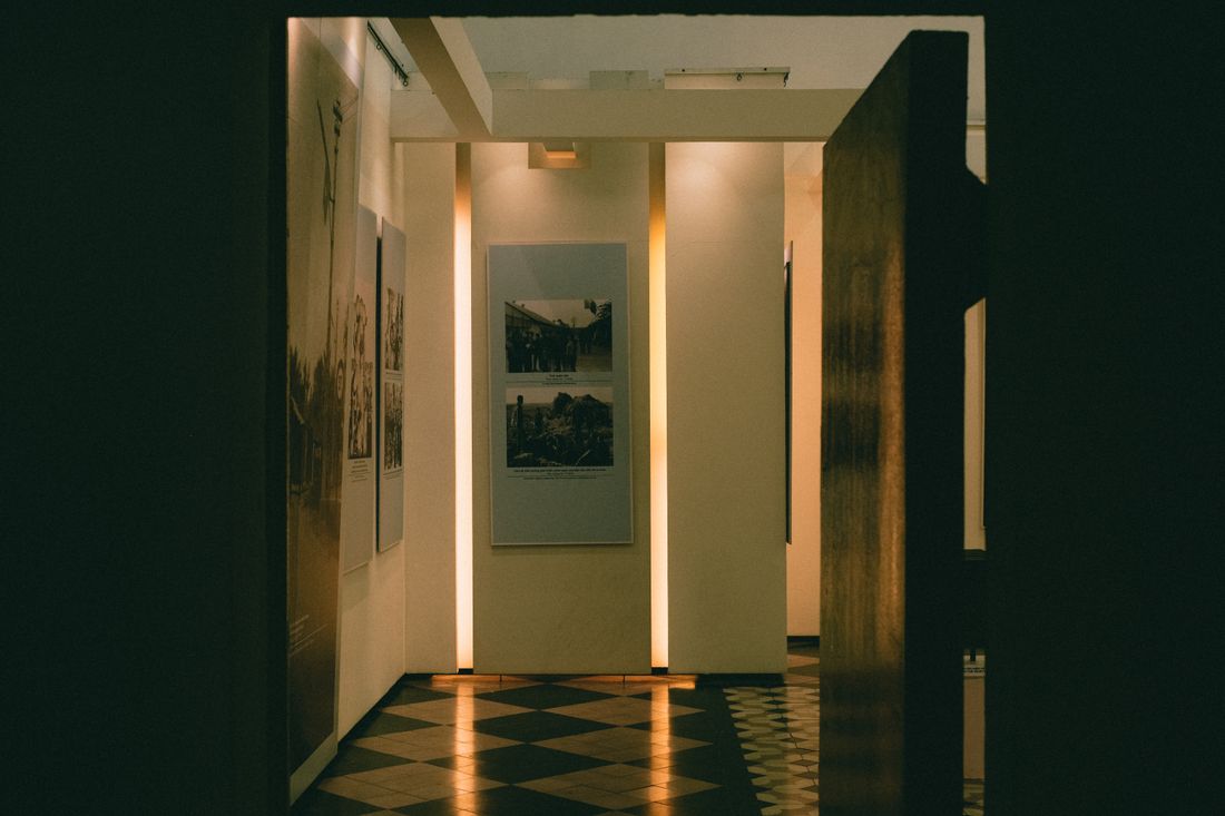 A dimly lit museum corridor with warm lighting and framed artworks displayed on the walls.