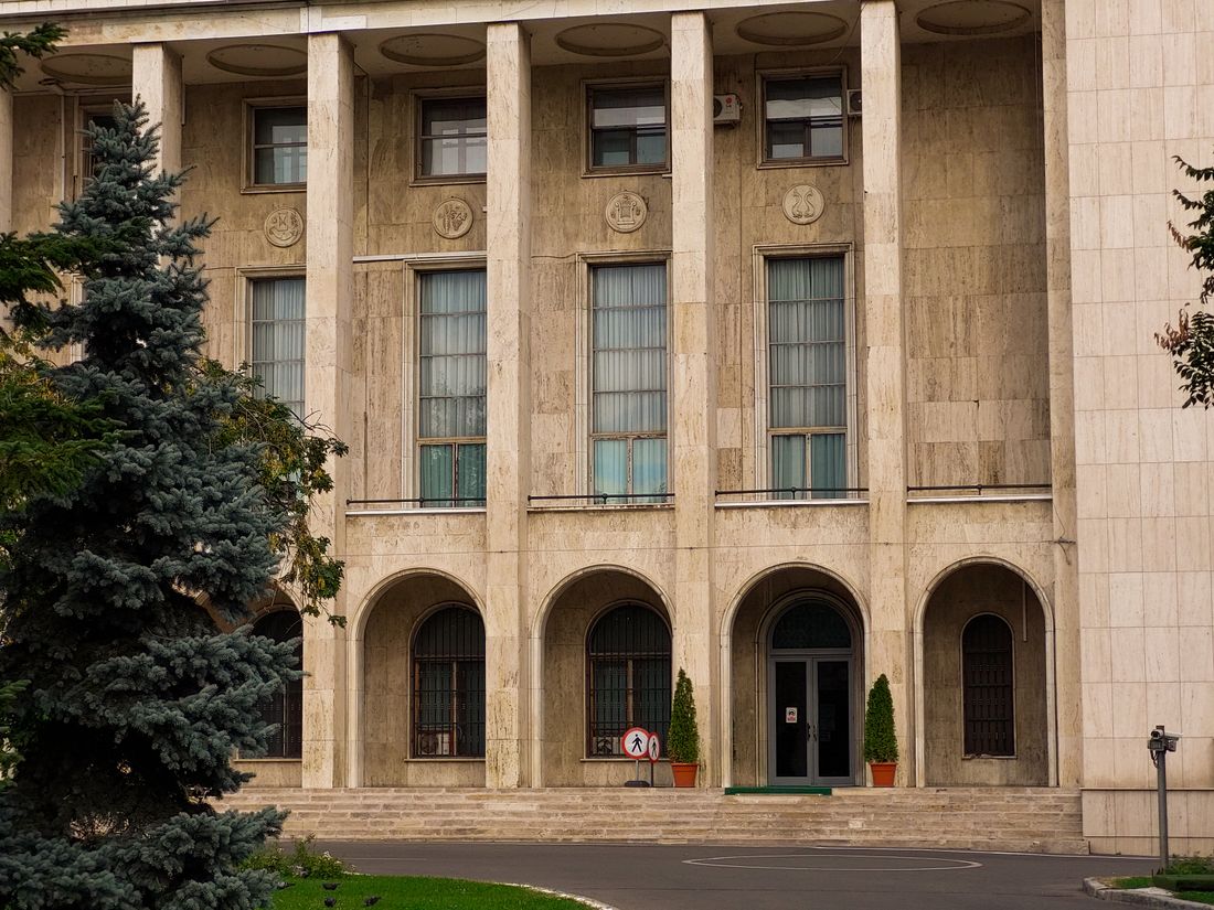 A formal government-style building facade with columns and arched entrances