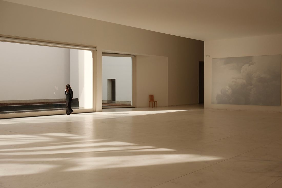 A wide, mostly empty gallery-like interior with plain walls, a hard floor, and daylight from tall windows