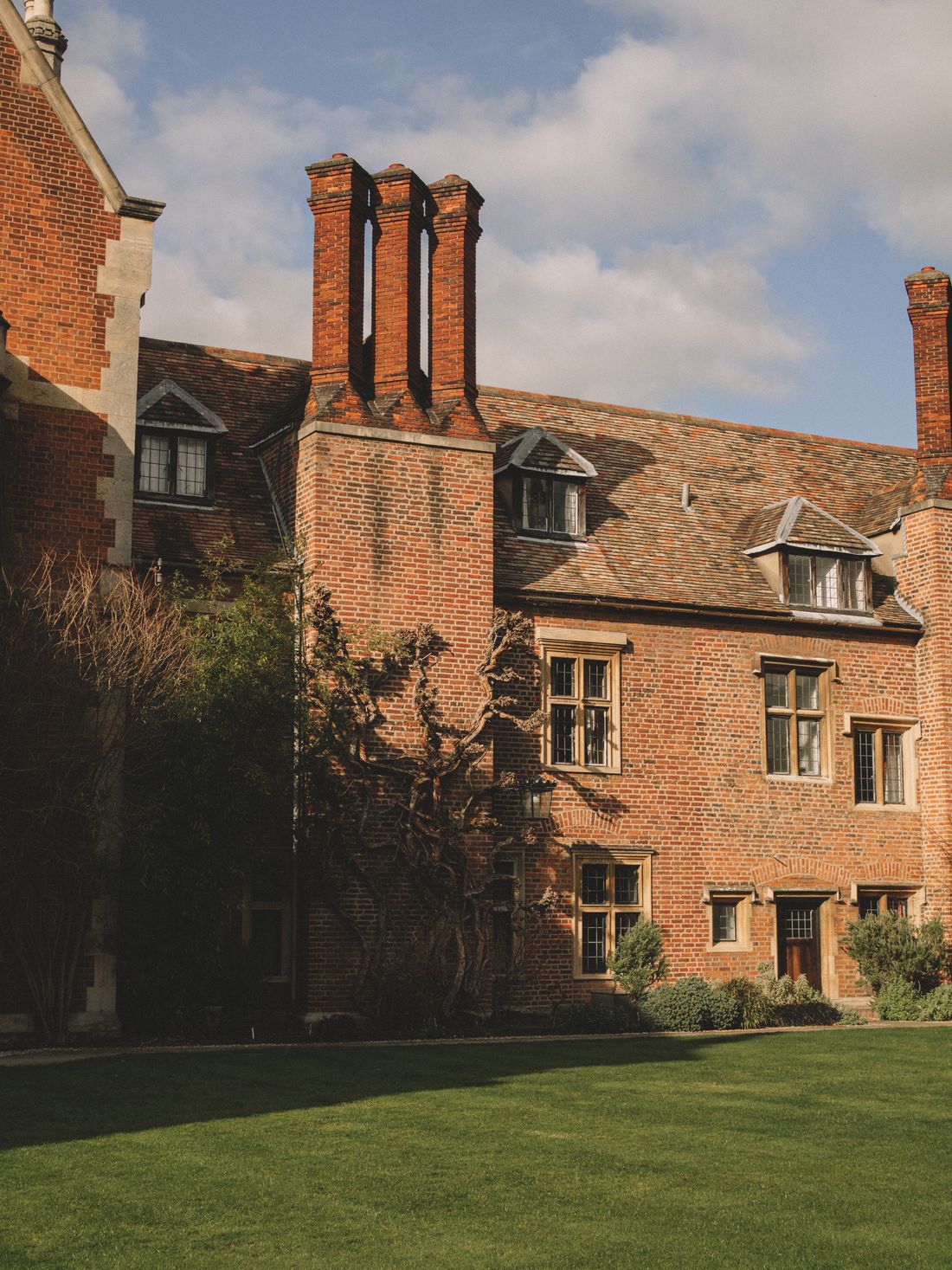 Historic brick academic building facade with ivy growing up the wall and a lawn in front