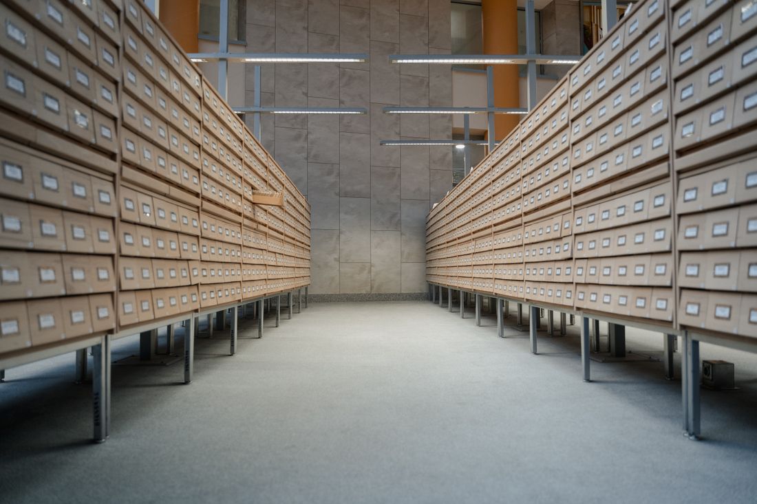 A long aisle of closed archival storage drawers stretching into the distance in an empty institutional room.