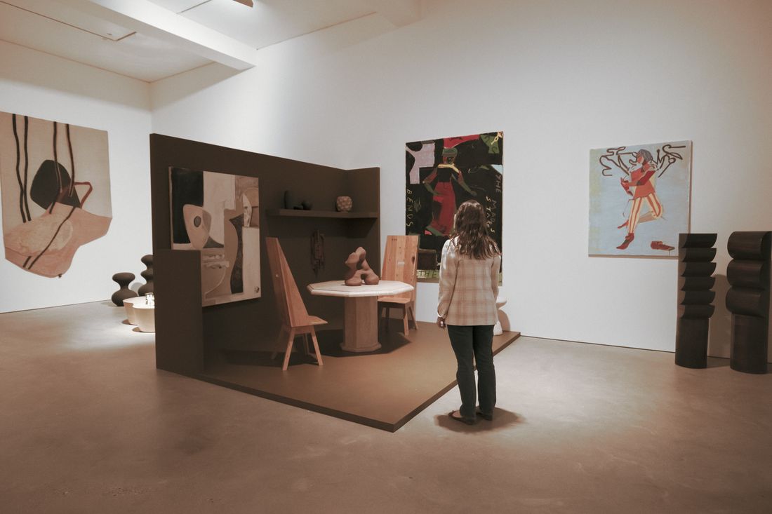 A visitor looking at objects and works arranged in a bright exhibition space