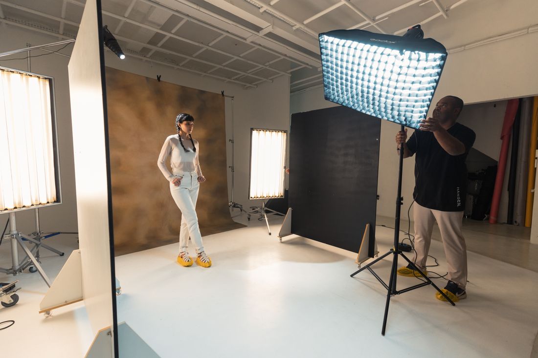 Photographer adjusting studio lighting around a portrait subject seated for a session