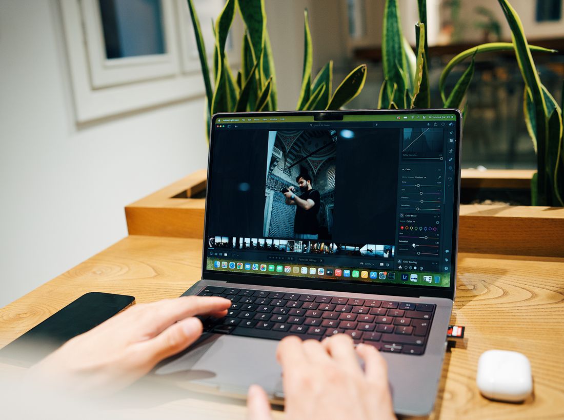 Photographer reviewing and editing portrait images on a laptop before sending a final package