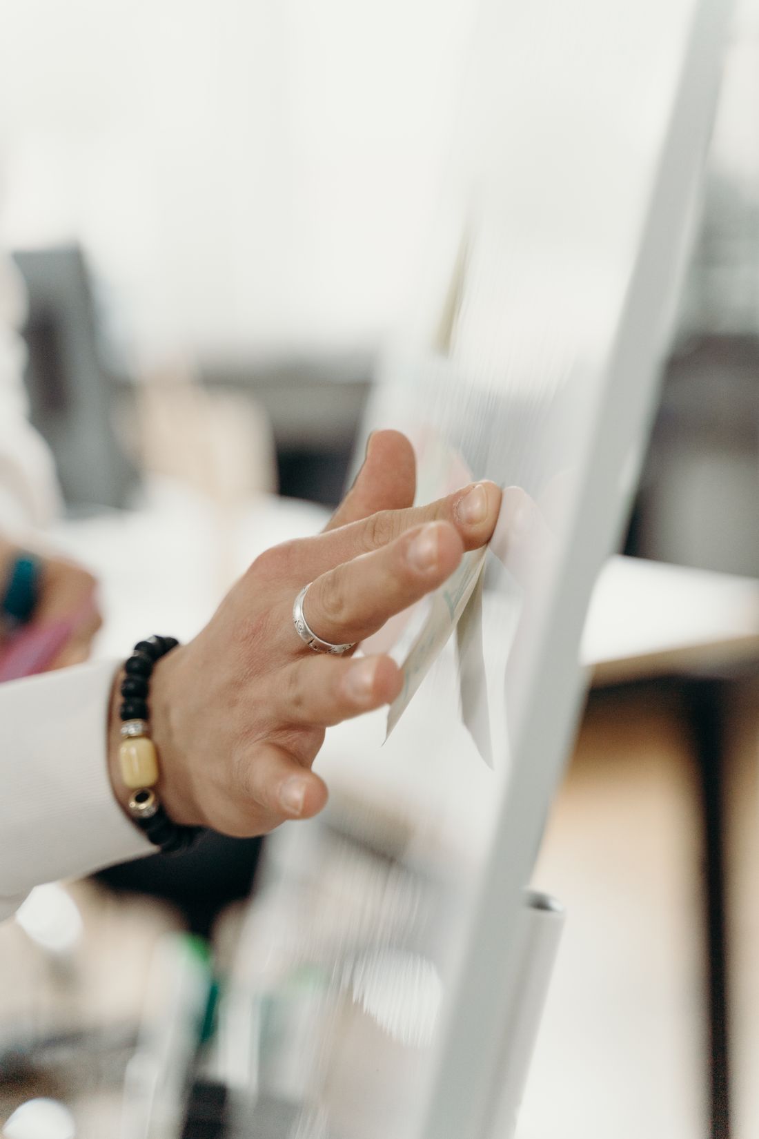 A hand interacting with a digital whiteboard in a bright office setting.