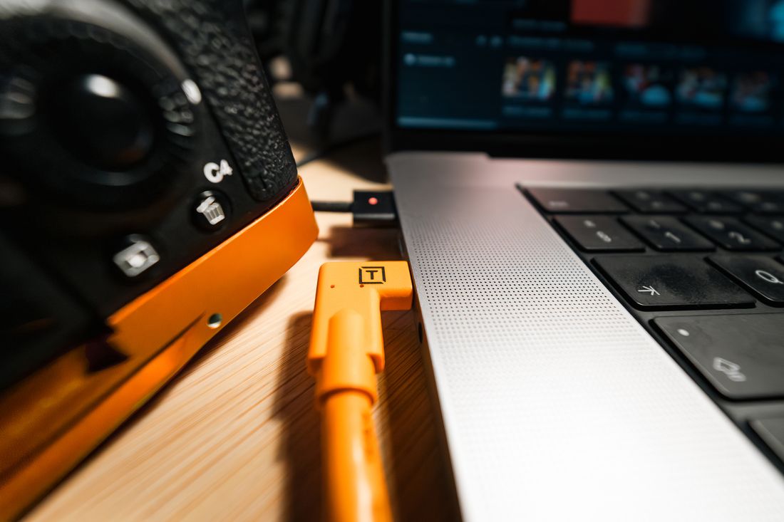 Close-up of a camera tethered to a laptop with a cable during a photo session