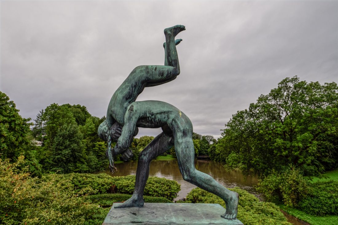 A bronze sculpture in a park under a flat, overcast sky