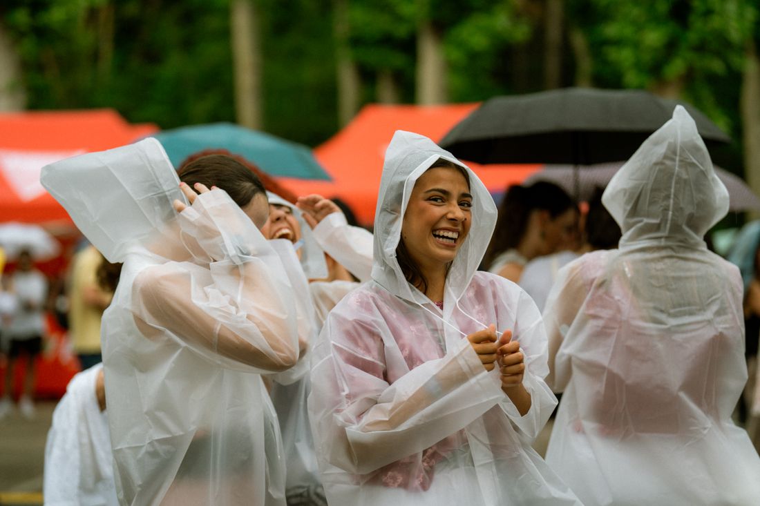 A group of people in rain ponchos laughing together at an outdoor event