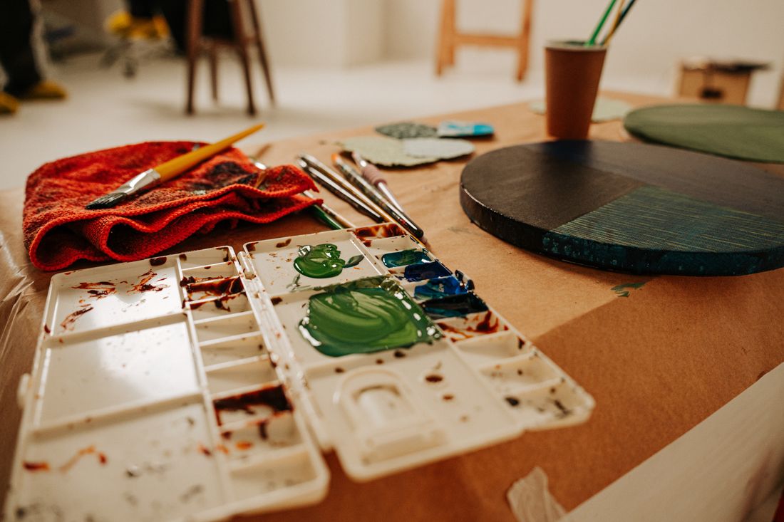 Overhead view of a watercolor palette, brushes, and paint tubes on a studio table