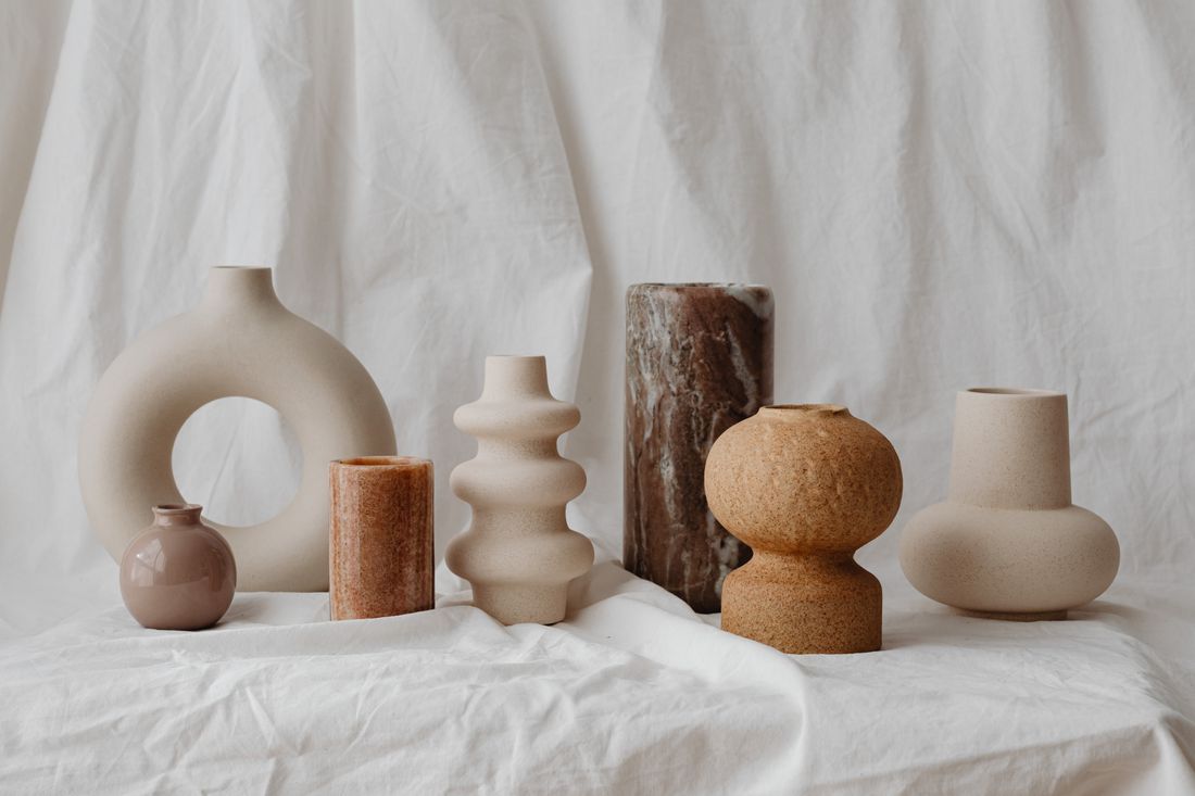 An assortment of ceramic vases in different forms, colors, and finishes arranged together on a neutral fabric backdrop