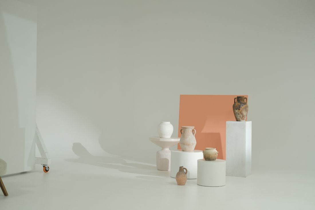 A group of matte ceramic vases in varied forms arranged on white fabric in a minimalist studio setup with soft shadows