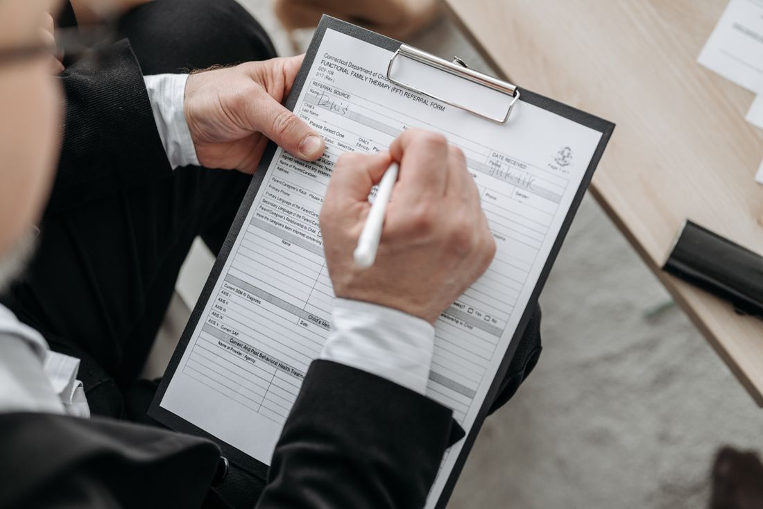 A close-up of hands signing a formal document on a clipboard