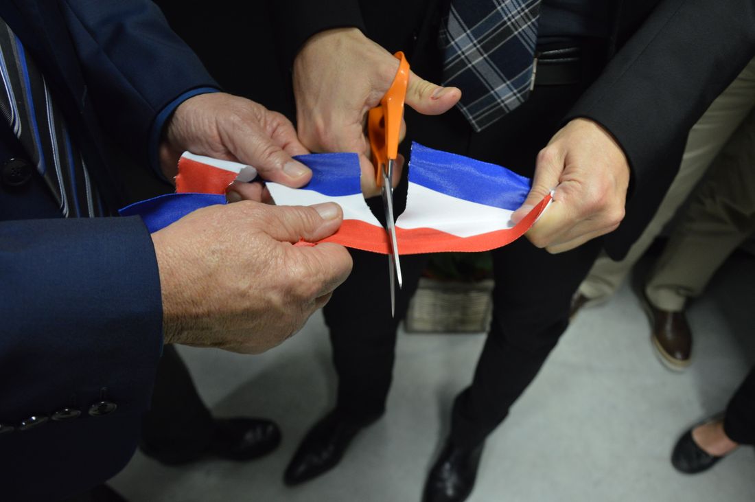 Close-up of hands cutting a ribbon with scissors at an opening ceremony