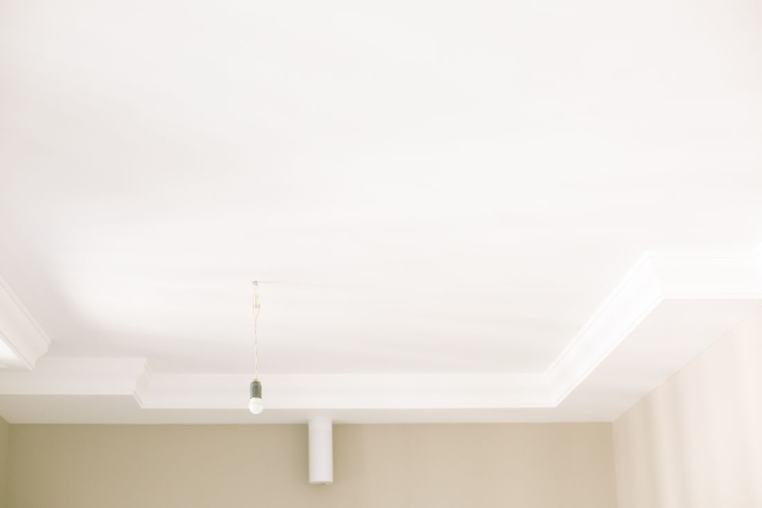 A single bare light bulb hanging from a plain white ceiling, representing the kind of mismatched fixture found in a converted non-gallery space.