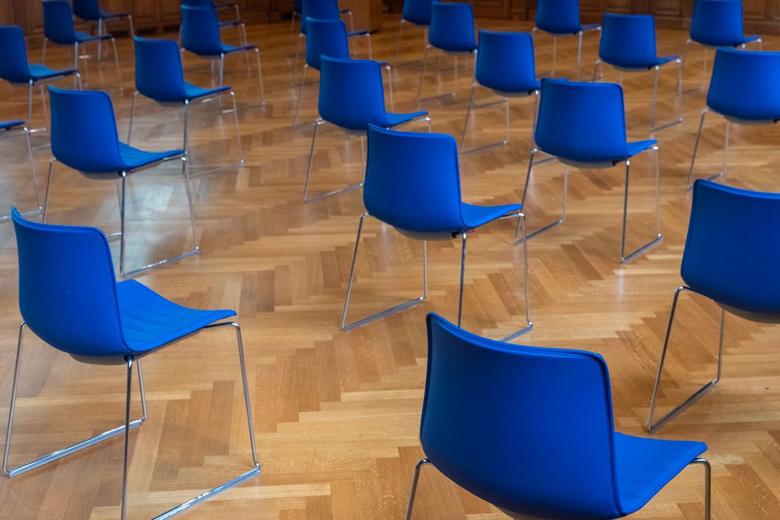 Rows of empty chairs arranged on a wood floor in a bright room, set up before an event
