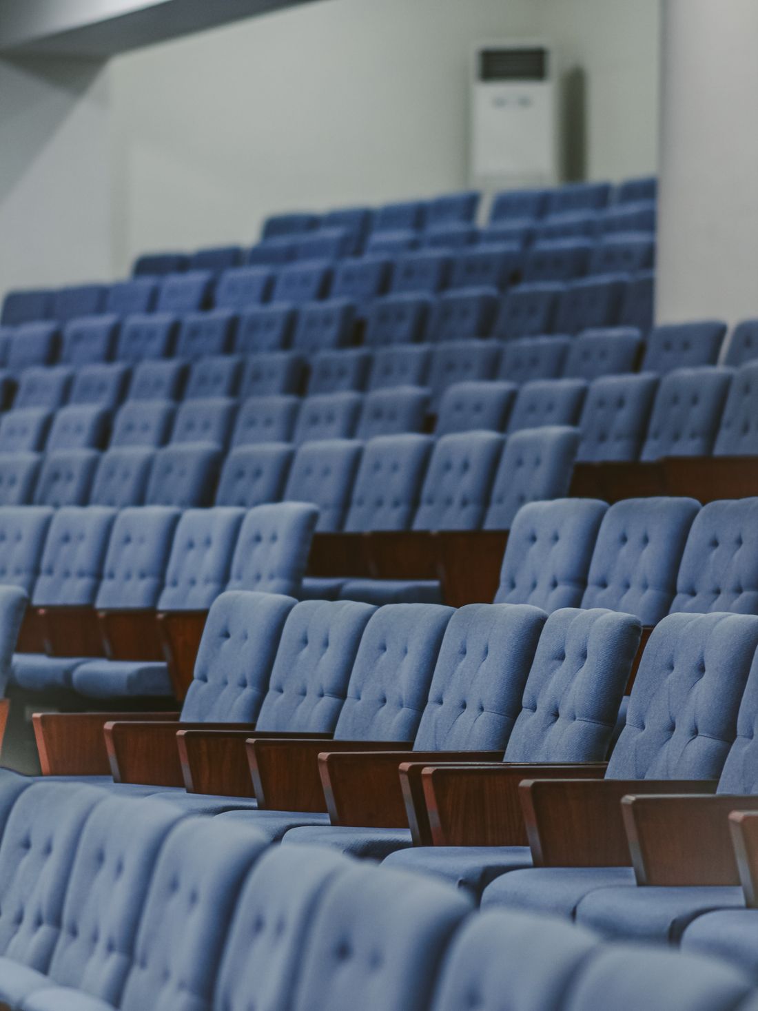 Rows of upholstered chairs arranged in a plain conference room, set for an event