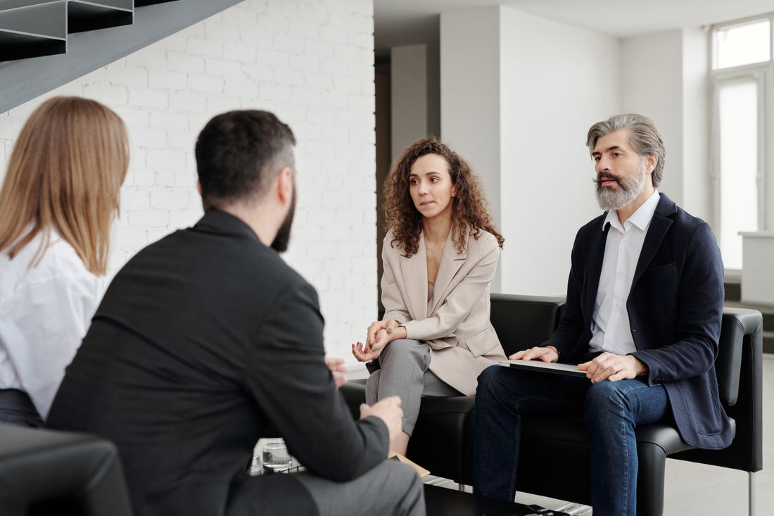 A small group of people in formal attire in quiet conversation indoors