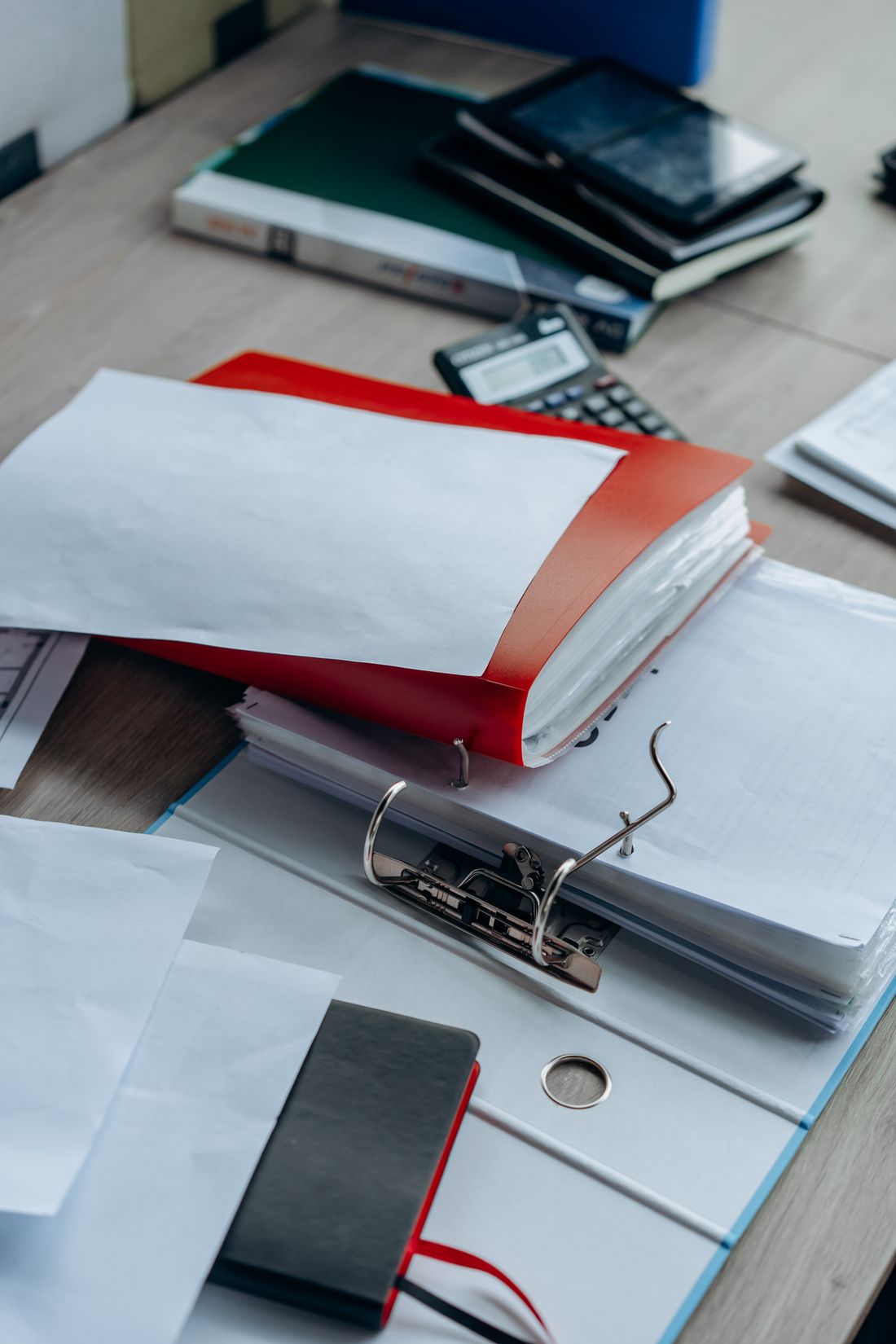 A tidy desk with binders, notebooks, and papers arranged near an entrance-style table