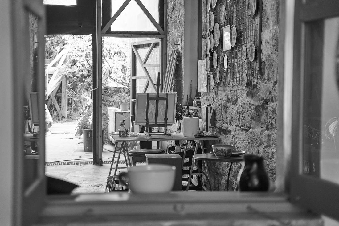 A view through an open studio doorway showing an easel, canvases, and materials mid-process, representing a working artist's room during a residency visit.