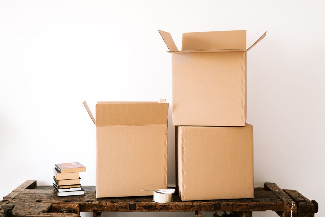 Plain cardboard boxes stacked against a bare white wall indoors