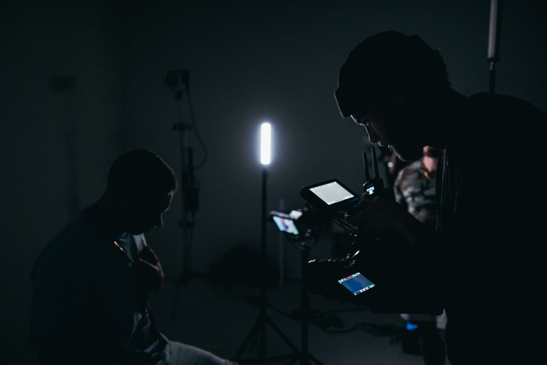 Silhouetted cinematographer adjusting camera and lighting equipment in a darkened studio