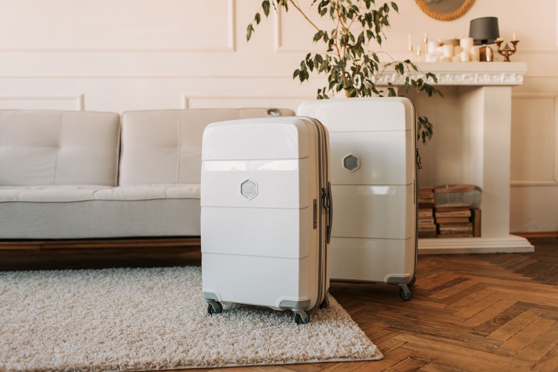 Two hard-shell cases standing in a bright, tidy living room next to a sofa and hardwood floor