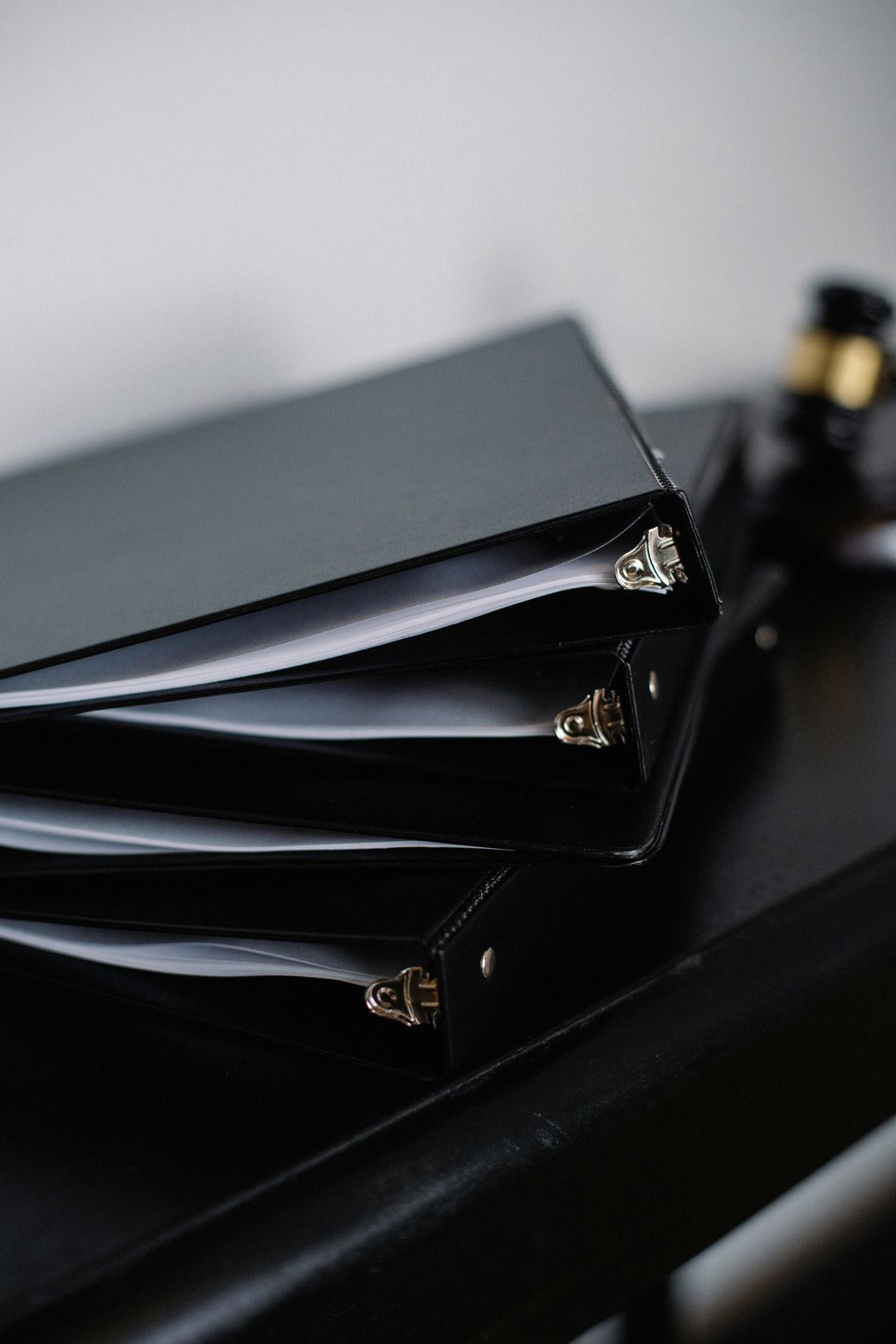 A stack of closed black binders on a desk, corners aligned in an orderly pile