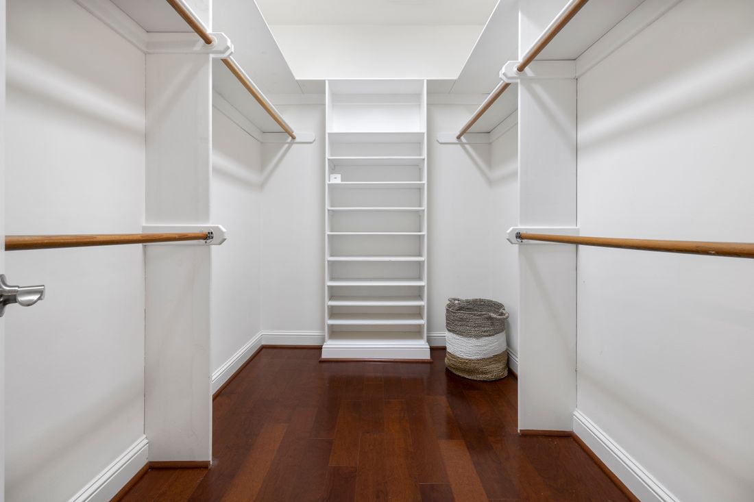 An organized, empty storage room with built-in shelving and a clean wood floor