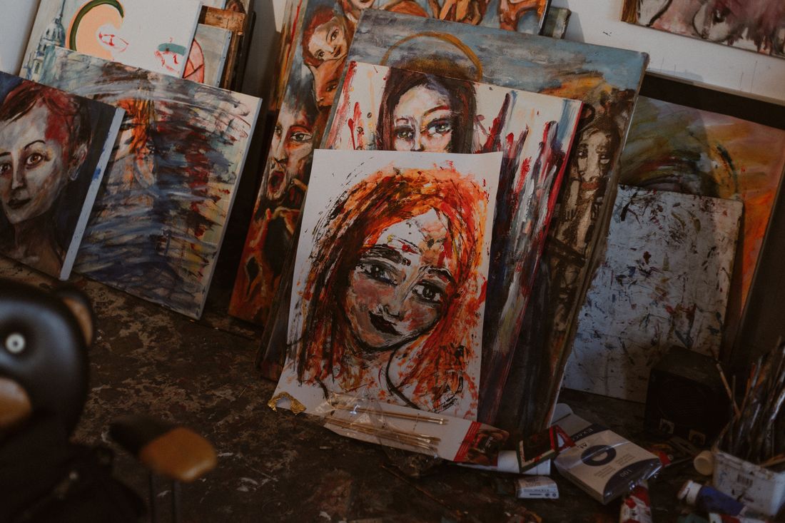 Multiple painted canvases piled and leaning together in a studio, representing a full body of work