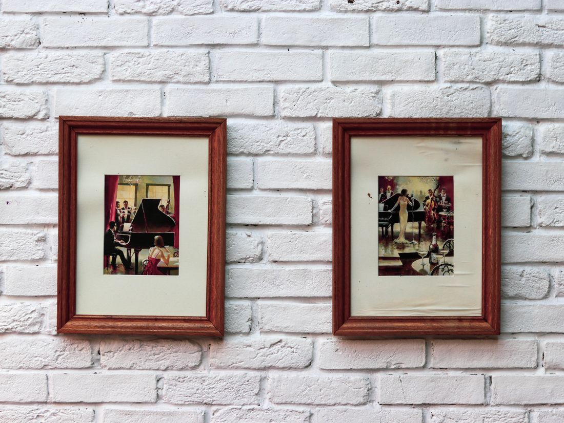 Two framed artworks hanging on a plain white wall in a finished space