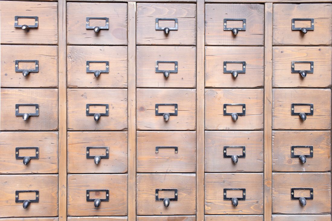 A wall of small labeled wooden archive drawers used for organized storage