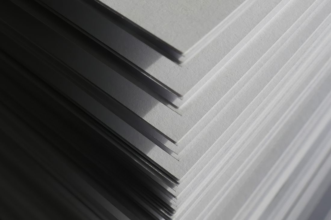 Close-up of the stacked edge of a run of paper sheets, representing a print edition