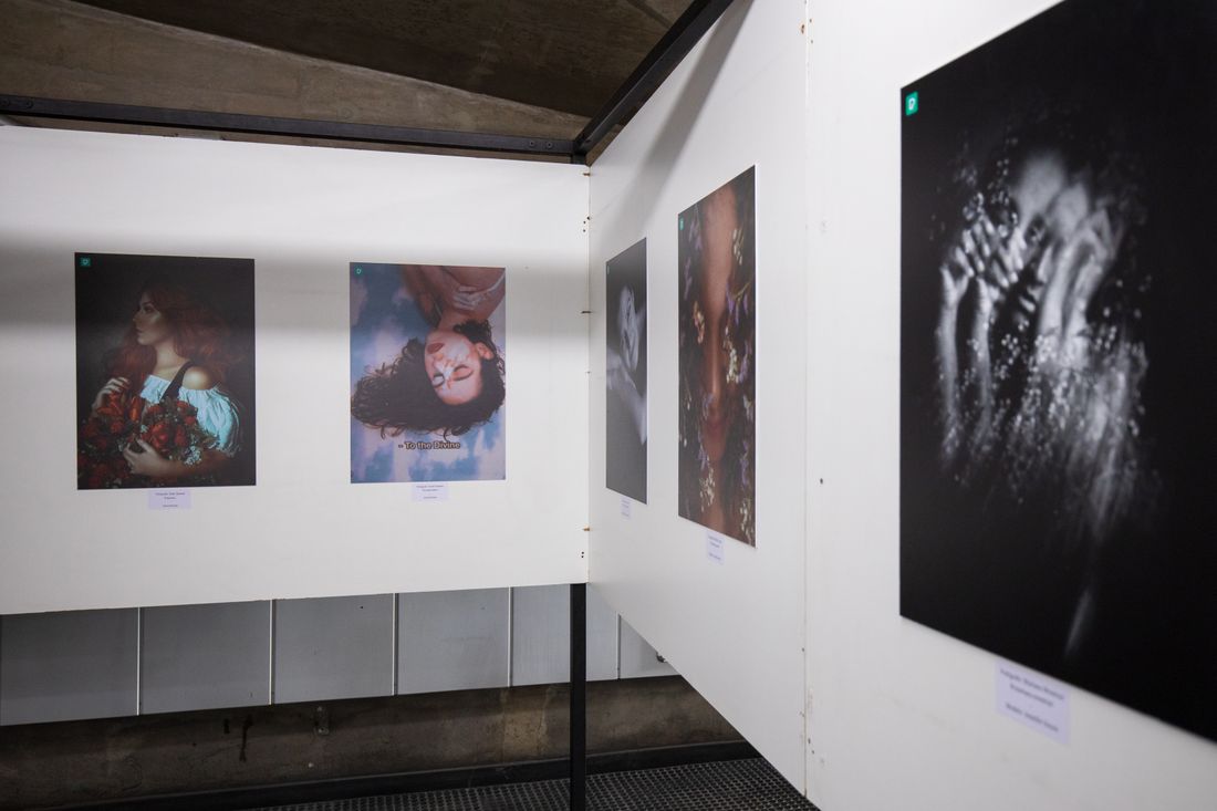 A narrow gallery corridor with framed photographic prints hung close together on angled walls