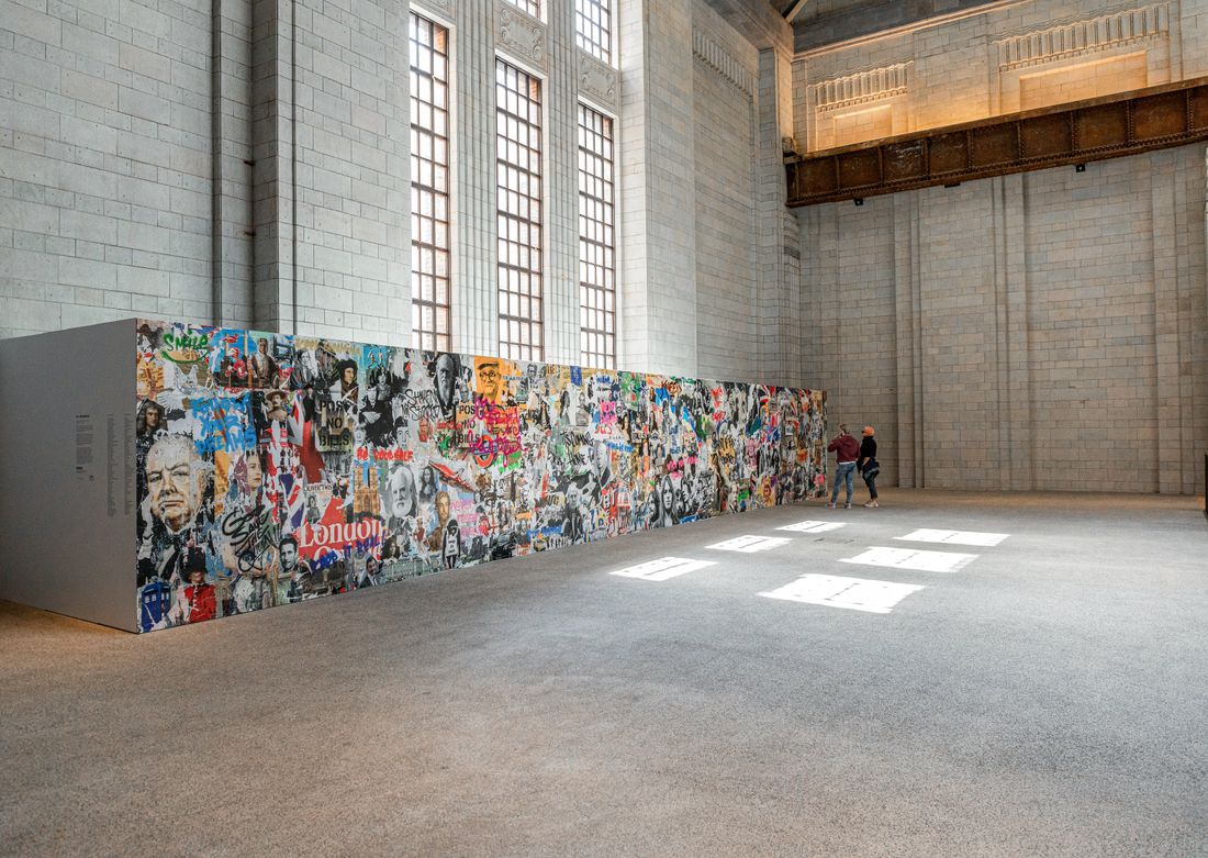 A colorful collage-style wall installation on view in a spacious exhibition hall, shown at full scale within the room