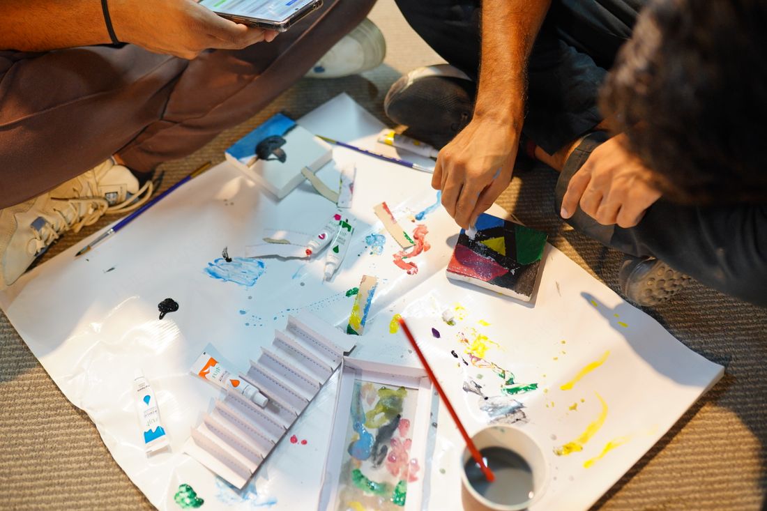 Adults working together at a hands-on painting workshop, mixing colors and creating art indoors