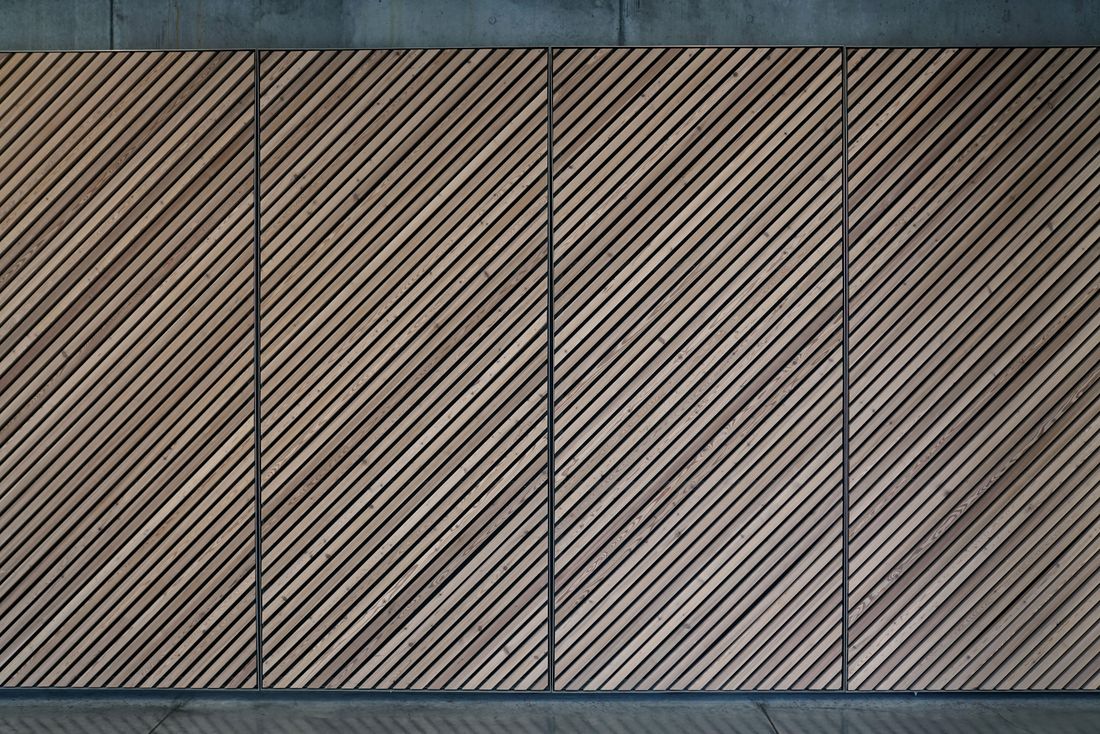 A close view of a diagonal wood-slat panel wall, the kind of acoustic-style wall treatment used to shape sound in a room.