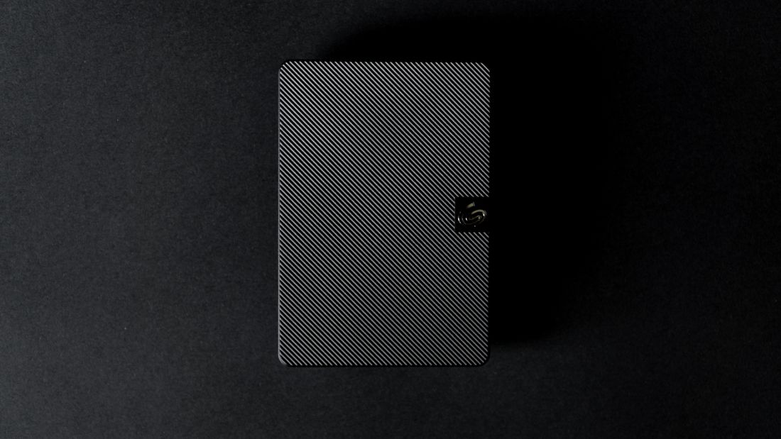 A sleek black external hard drive photographed from above against a dark background