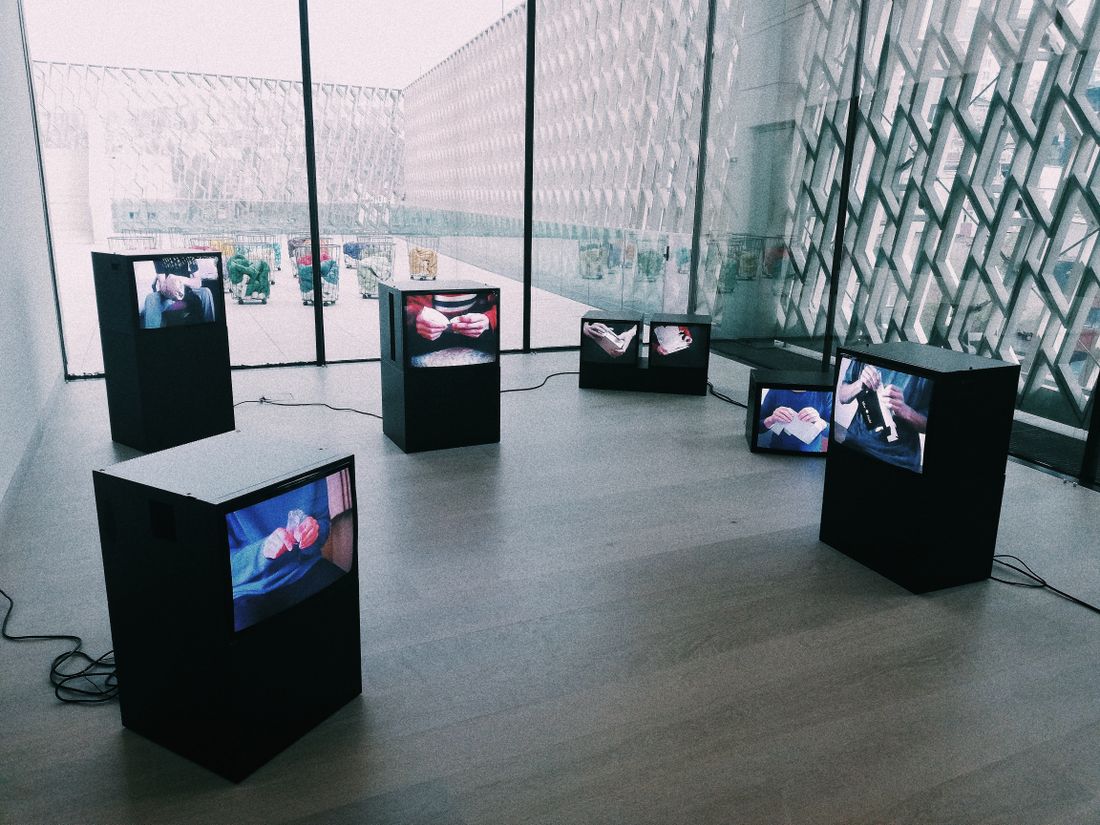 Several freestanding screens on pedestals playing video content in a bright gallery space
