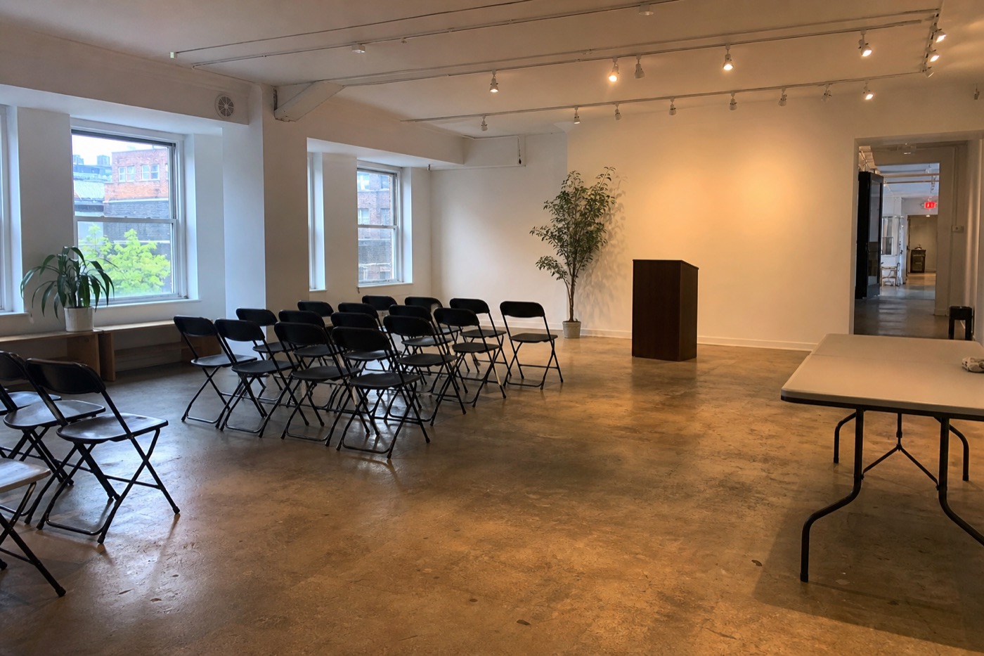 Empty contemporary event room with chairs, a lectern, clear walkways, and mixed daylight before guests arrive