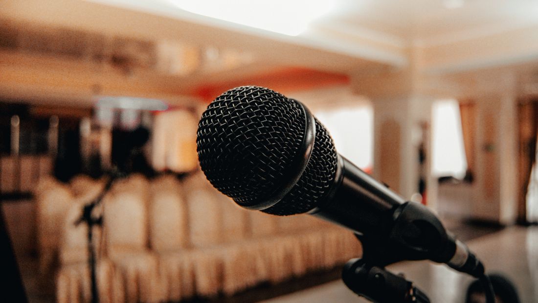 Close-up of a black microphone on a stand in a softly lit, empty conference room