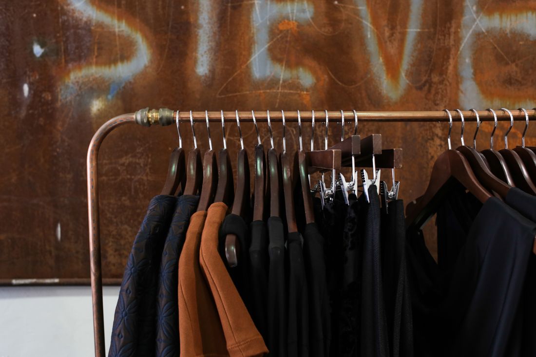 A rack of clothes on wooden hangers in a boutique wardrobe room