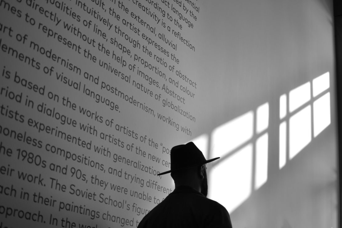 A visitor's shadow cast across a museum wall while reading the exhibition text