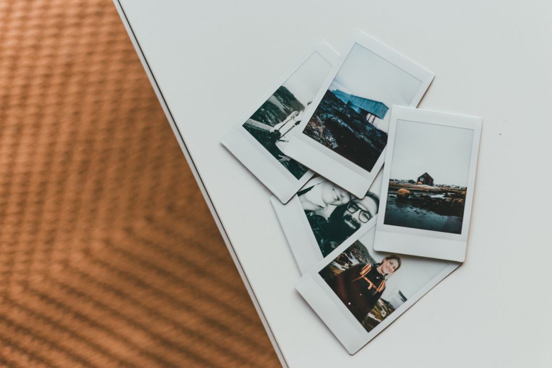 A loose spread of instant photo prints scattered on a plain white table