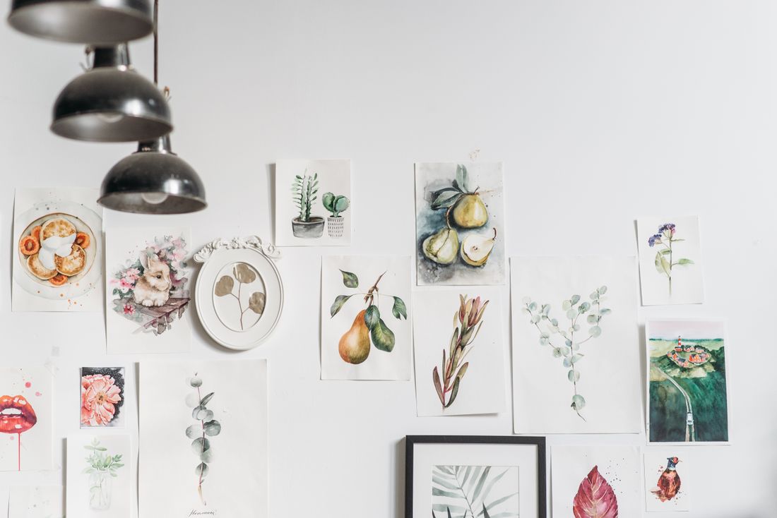 A curated wall of framed artworks arranged closely together in a studio