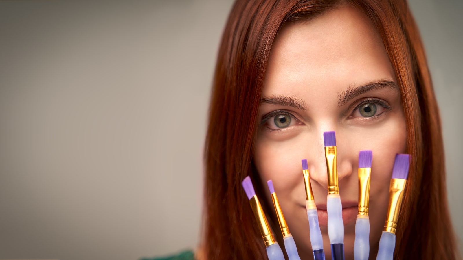 Close view of a painter behind a fanned row of brushes, a detail shot that carries a short vertical clip on its own