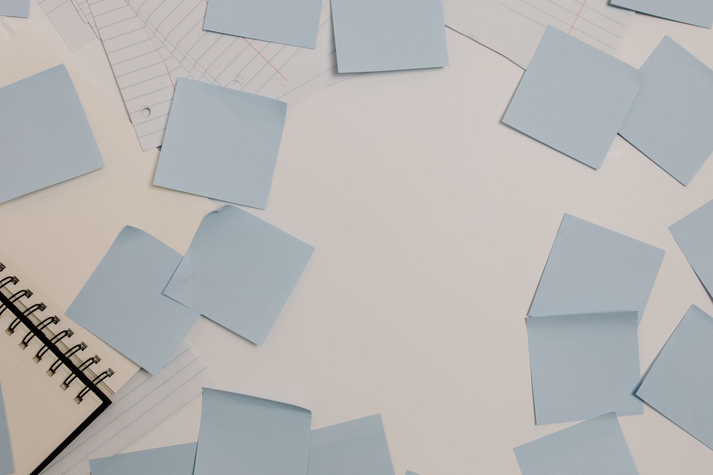 Top-down view of a desk with blue sticky notes, a spiral notepad, and lined papers used for planning