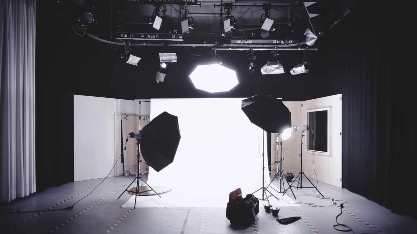 Empty photography studio with two softbox lights positioned on either side of a plain backdrop