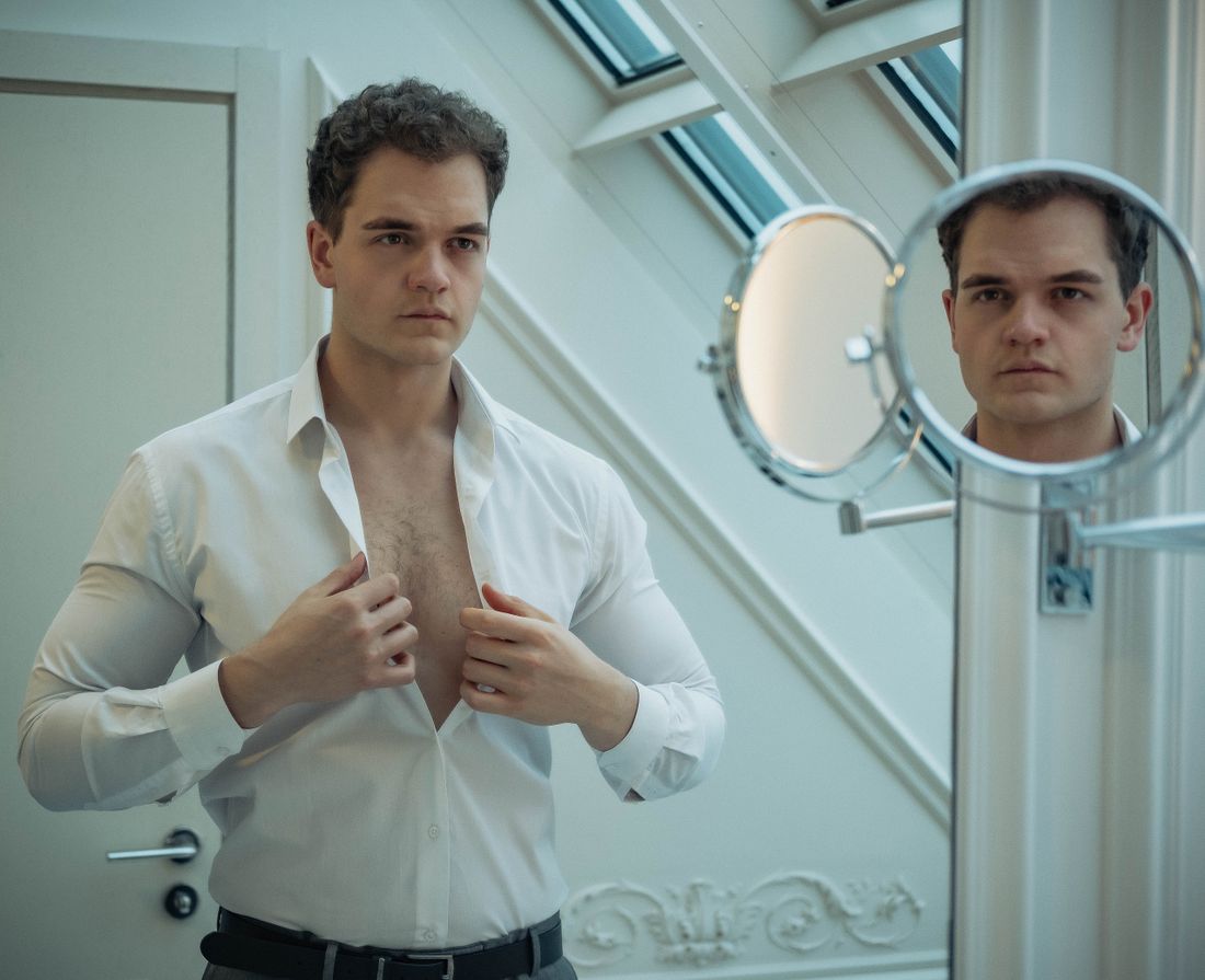 A person buttoning a shirt in front of a mirror while getting ready